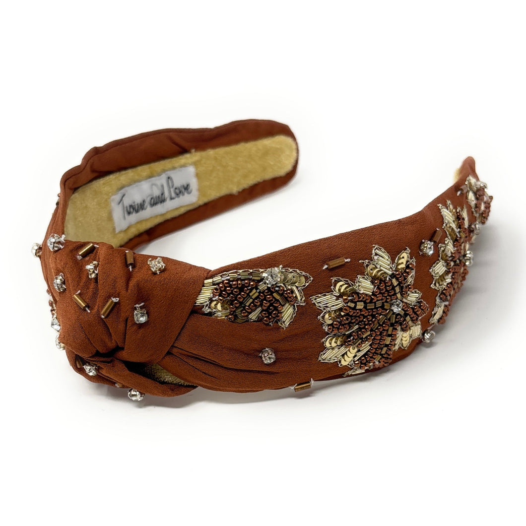 Brown headband with floral embellishments on a white background