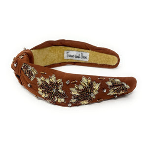 Brown headband with floral embellishments on a white background