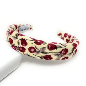 ivory-colored fabric headband with a pattern of burgundy roses and green leaves on a white background. The headband is slightly arched, creating a soft, delicate look.