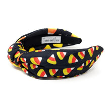 Load image into Gallery viewer, A black headband with colorful candy corn print, featuring white, orange, and yellow. Fun, Halloween-themed accessory.