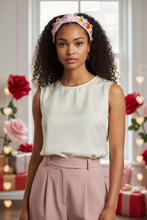 Load image into Gallery viewer, Woman wearing a white sleeveless top and pink pants with a valentine headband, standing in a decorated room with flowers and lights.