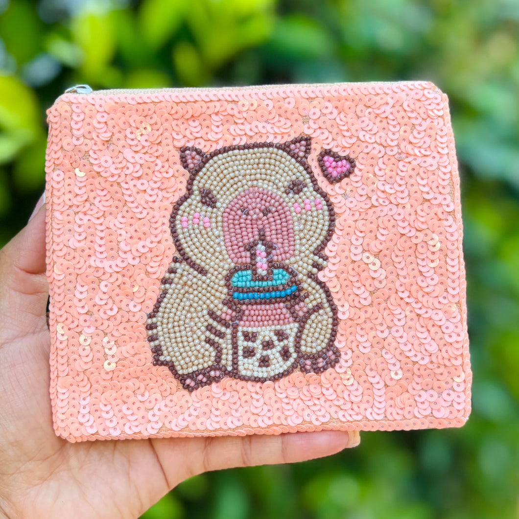 Sequined pouch with a beaded design of a capybara sipping bubble tea, featuring a small pink heart. Playful and whimsical vibe.
