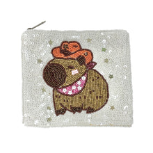 Load image into Gallery viewer, Sequined pouch featuring a cute capybara wearing an orange cowboy hat and pink bandana. Background covered in shiny white sequins, playful tone.