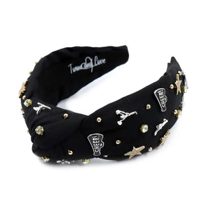 Black headband adorned with gold and silver embellishments, including stars, cheerleaders, and rhinestones, exuding a playful and glamorous vibe.