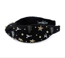 Load image into Gallery viewer, Black headband adorned with gold and silver embellishments, including stars, cheerleaders, and rhinestones, exuding a playful and glamorous vibe.