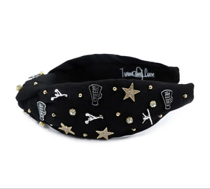Black headband adorned with gold and silver embellishments, including stars, cheerleaders, and rhinestones, exuding a playful and glamorous vibe.