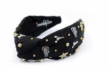 Load image into Gallery viewer, Black headband adorned with gold and silver embellishments, including stars, cheerleaders, and rhinestones, exuding a playful and glamorous vibe.