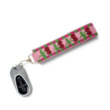 Load image into Gallery viewer, Side view of a handcrafted cherry beaded wristlet keychain with a pink background, green checker border, and gold-tone lobster clasp.