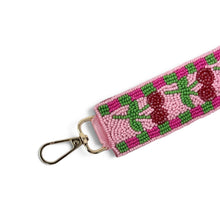 Load image into Gallery viewer, Side view of a handcrafted cherry beaded wristlet keychain with a pink background, green checker border, and gold-tone lobster clasp.