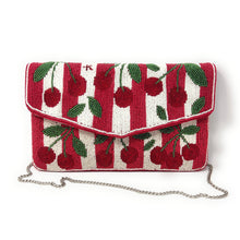 Load image into Gallery viewer, A red and white beaded clutch bag with a cherry pattern, featuring a silver chain strap, photographed on a white background.