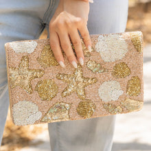 Load image into Gallery viewer, Handcrafted seashell clutch purse featuring gold and ivory sequined ocean motifs on a nude background.