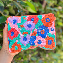 Load image into Gallery viewer, Colorful beaded floral clutch held by a hand with a green leafy background
