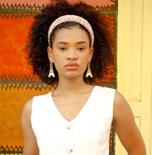 Load image into Gallery viewer, Woman wearing a sprinkles padded headband a with white sleeveless top and blue jeans against a colorful wall.