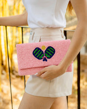Load image into Gallery viewer, Person holding a pink clutch with a pickleball motif 
