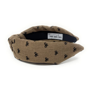 Brown headband with a knotted design, featuring small black bow patterns. The inside tag reads "Time and Love." The tone is stylish and elegant.