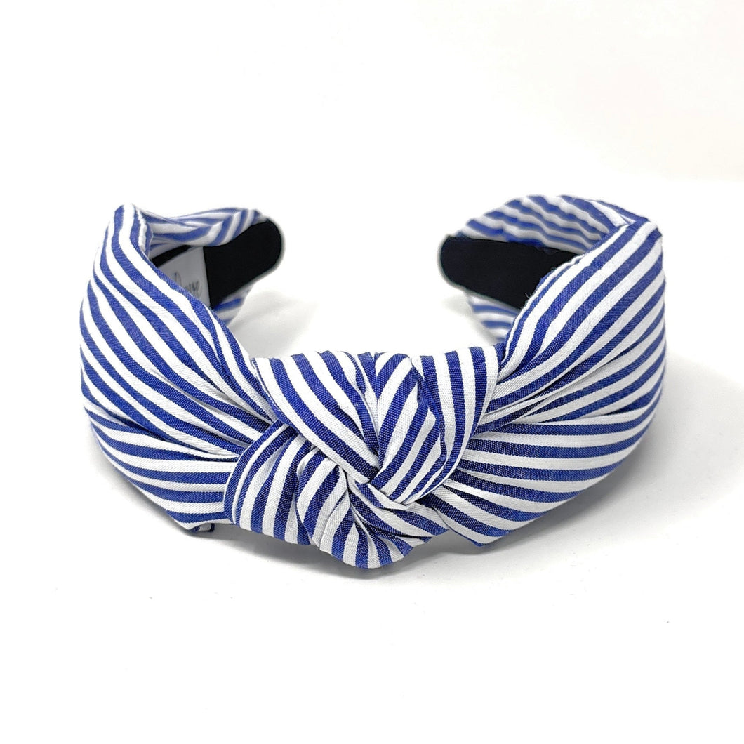 Blue and white striped headband with a knotted detail in the center, set against a plain white background, conveying a trendy, nautical style.