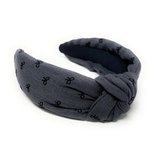Load image into Gallery viewer, A blue headband with a knotted design, featuring small black bow patterns. The inside tag reads &quot;Time and Love.&quot; The tone is stylish and elegant.