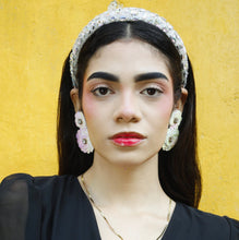 Load image into Gallery viewer, Chic fashion look featuring a beaded pearl headband paired with oversized flower earrings, styled with a black wrap crop top.