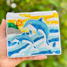 Load image into Gallery viewer, Beaded pouch featuring two blue dolphins jumping over stylized ocean waves. Background includes a yellow sun with spirals and green hills.