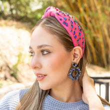 Load image into Gallery viewer, Stylish close-up featuring a jeweled pink headband paired with bold blue rhinestone drop earrings and a cozy knit sweater.