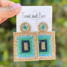 Load image into Gallery viewer, Geometric beaded statement earrings featuring turquoise, navy, green, and gold square patterns with intricate embroidery.
