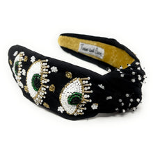 Load image into Gallery viewer, Black knotted headband adorned with beaded evil eye motifs, pearls, and gold accents, worn by a model outdoors.