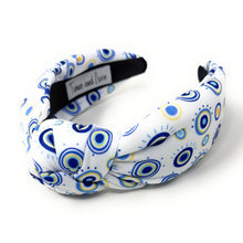 Load image into Gallery viewer, A white padded headband features a blue and yellow concentric circle pattern, exuding a playful vibe.