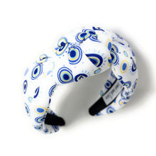 Load image into Gallery viewer, A white padded headband features a blue and yellow concentric circle pattern, exuding a playful vibe.