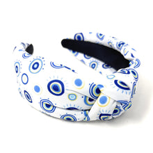 Load image into Gallery viewer, A white padded headband features a blue and yellow concentric circle pattern, exuding a playful vibe.