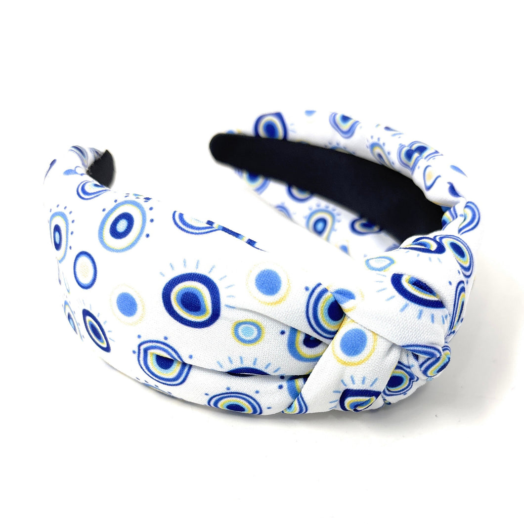 A white padded headband features a blue and yellow concentric circle pattern, exuding a playful vibe.