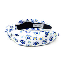 Load image into Gallery viewer, A white padded headband features a blue and yellow concentric circle pattern, exuding a playful vibe.