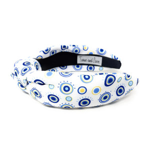 A white padded headband features a blue and yellow concentric circle pattern, exuding a playful vibe.