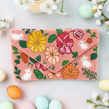 Load image into Gallery viewer, Pink beaded clutch with floral and animal designs on a light blue background with Easter eggs and flowers.
