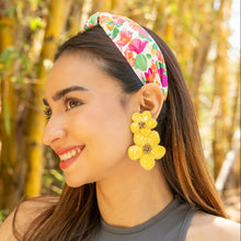 Load image into Gallery viewer, Fashion portrait featuring a vibrant floral knot headband and bright yellow beaded flower drop earrings in natural sunlight.