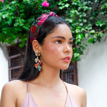 Load image into Gallery viewer, Model styled in a bold floral headband and jeweled statement earrings against a lush garden background.