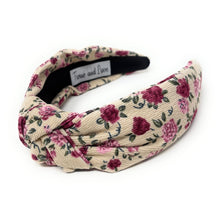 Load image into Gallery viewer, Floral patterned headband with a visible brand label on a white background