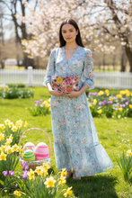 Load image into Gallery viewer, Woman in a floral dress holding a laptop in a garden with Easter eggs and flowers.