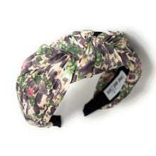 Load image into Gallery viewer, A floral patterned headband with a knot design, featuring shades of green, purple, and pink. It sits against a plain white background, conveying a stylish and feminine tone.