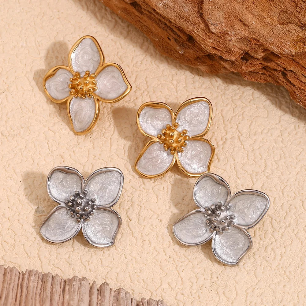 Floral earrings with gold and silver finishes on a textured beige surface
