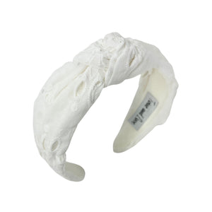 White headband with intricate white floral embroidery, displayed in a side view. The soft texture and elegant design convey a stylish, timeless appeal.