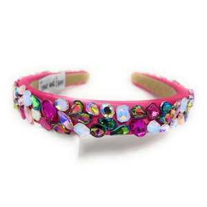 A vibrant pink headband adorned with multicolored gemstones, including blue, purple, and green. It exudes a playful, glamorous vibe.