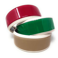 Load image into Gallery viewer, Three glossy patent headbands stacked together in red, emerald green, and beige with ivory trim on a white background
