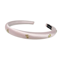 Load image into Gallery viewer, A satin pink headband adorned with small gold embellishments lies on a white background. The delicate design conveys elegance and sophistication.