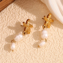 Load image into Gallery viewer, Gold earrings with pearl drops on a textured beige surface