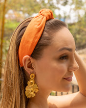 Load image into Gallery viewer, Elegant pumpkin-orange padded headband worn with large gold flower earrings, creating a chic and sophisticated look.