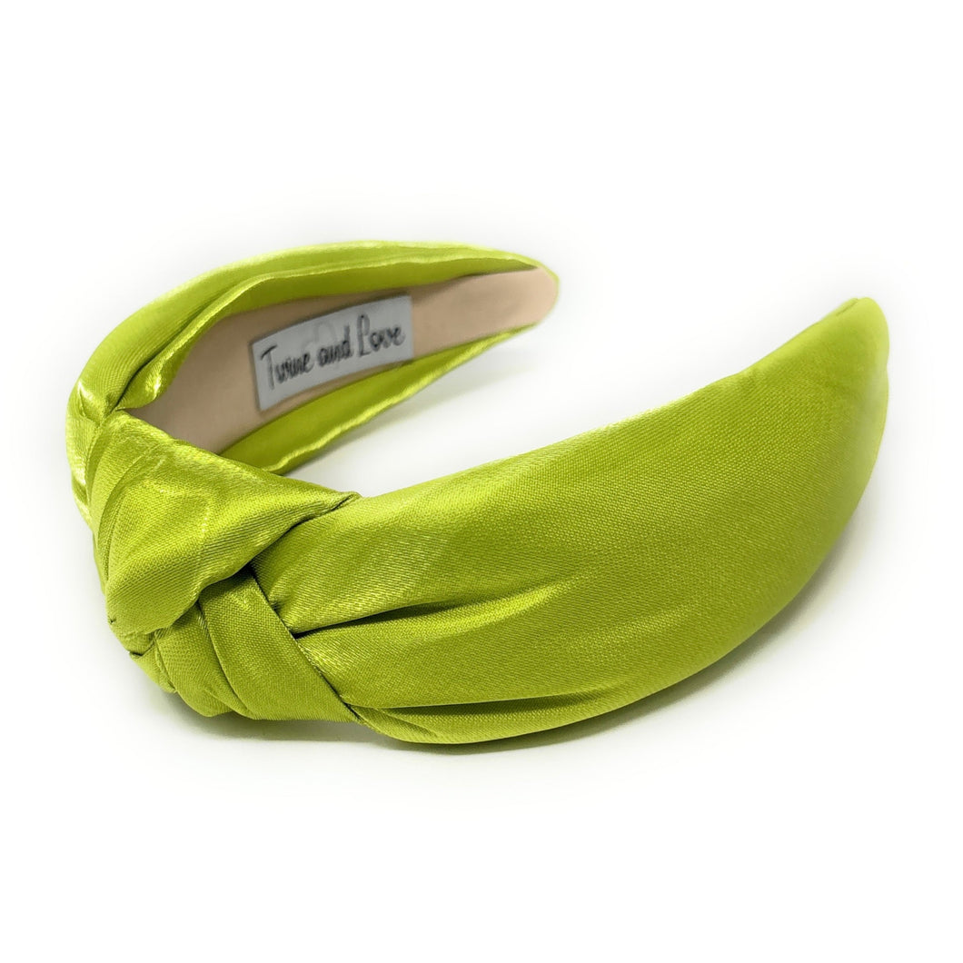 A vibrant green satin headband with a twisted knot design, labeled 