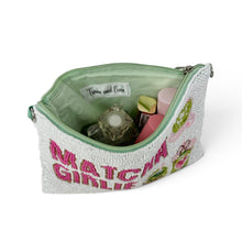 Load image into Gallery viewer, A light green textured cosmetic pouch with a light green interior and zipper, featuring 'MATCHA GIRLIE' in pink. The pouch is shown open, filled with various makeup items, on a clean white background.