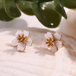 Delicate flower-shaped earrings with white petals and gold center on a white background. They emit an elegant, sophisticated tone.