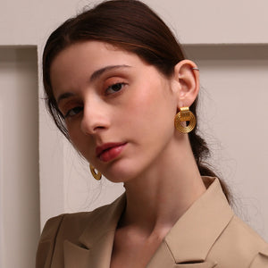 Woman wearing gold hoop earrings with a neutral background