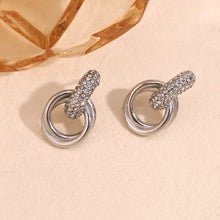 Load image into Gallery viewer, Pair of silver earrings with intricate designs on a beige background